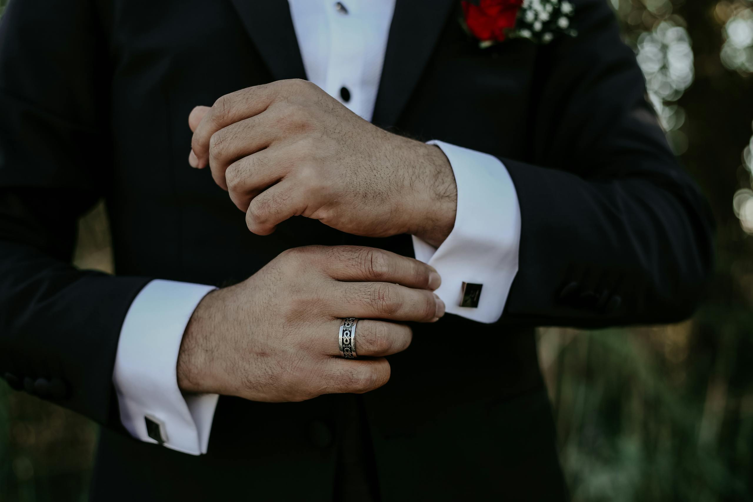 Close-up of a groom adjusting cufflinks on a wedding day.